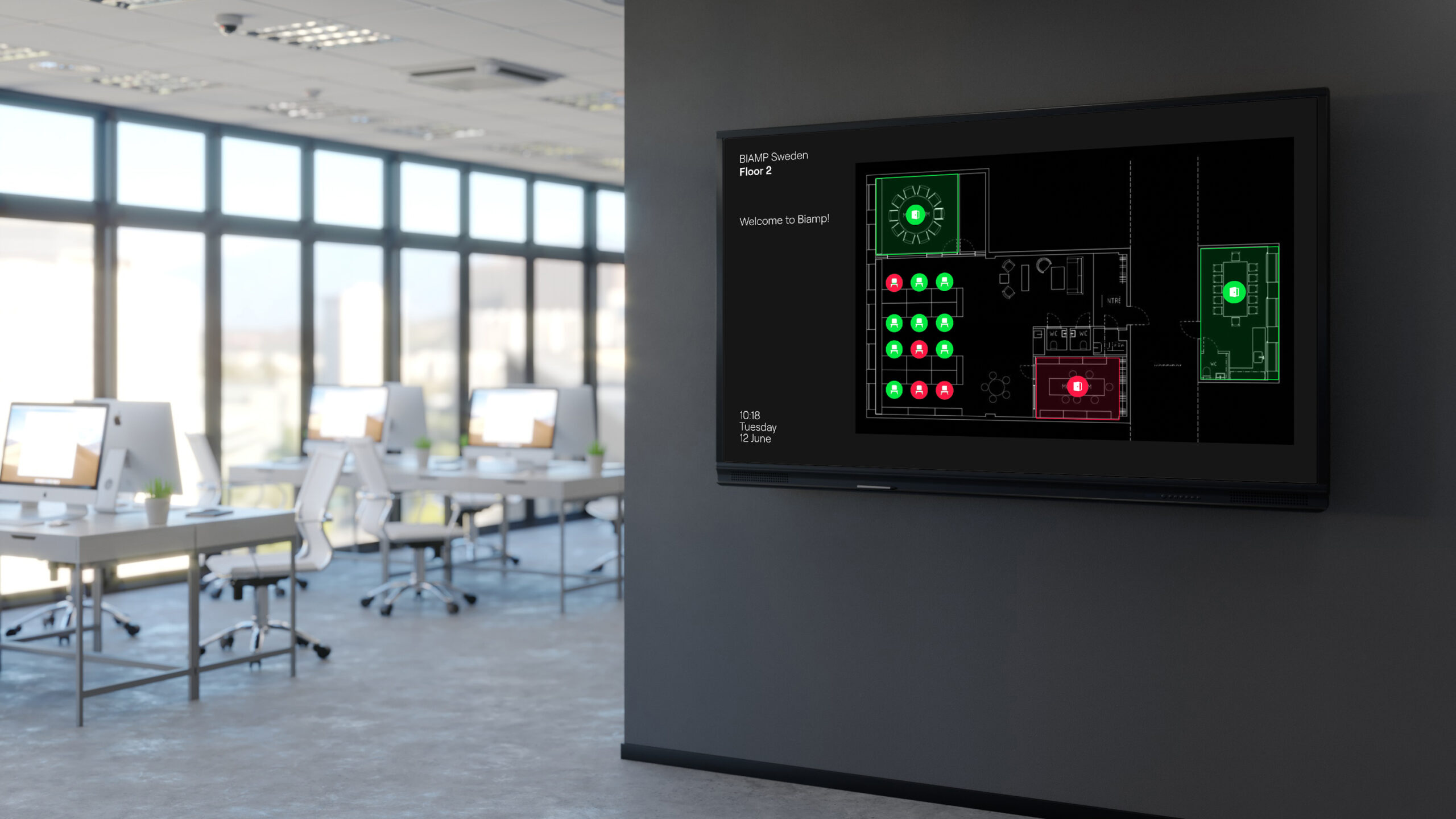 An open office with a wall-mounted Biamp display showing a floor plan of bookable spaces